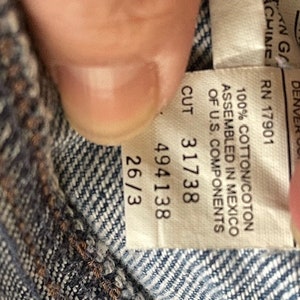 May include: A white tag with black text that reads "100% Cotton/Coton Assembled in Mexico of U.S. Components Cut 31738 494138 26/3 RN 17901 WASH/INT 8500 ZUN DENVER CO. ANG CHINE"