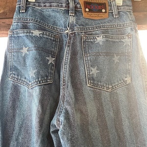 May include: Blue denim jeans with a white star pattern and a brown leather patch that says "Authentic Rockies World Champion Fit from the Denim City".