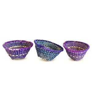 Peut inclure: Trois petits paniers tissés aux tons de violet et de bleu. Les paniers ont une forme arrondie avec un motif tissé et un bord contrastant. Les paniers sont présentés sur un fond blanc.