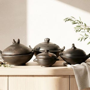 Peut inclure: Un ensemble de quatre marmites de cuisine en céramique brun foncé avec couvercles. Les marmites sont de tailles différentes, avec des formes arrondies et des poignées. Les couvercles présentent des éléments décoratifs uniques. Sur une surface en bois clair.
