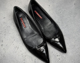 Zapatos planos Prada de charol negro con punta puntiaguda y logotipo metálico, raros