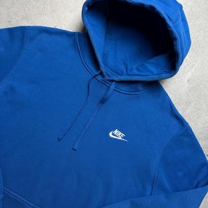 Peut inclure: Un sweat &agrave; capuche bleu royal avec un logo Nike blanc sur le devant.