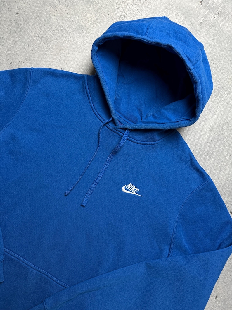 Peut inclure: Un sweat &agrave; capuche bleu royal avec un logo Nike blanc sur le devant.