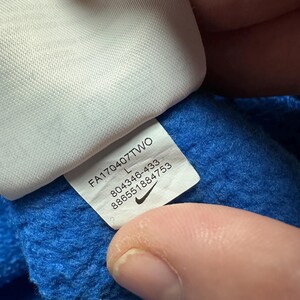 Peut inclure: Une &eacute;tiquette blanche avec du texte noir et un logo Nike swoosh. L'&eacute;tiquette indique "FA170407T7WO L 804346-433 8866551884753".