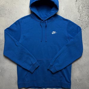 Peut inclure: Un sweat-shirt &agrave; capuche bleu avec un logo Nike blanc sur le devant.