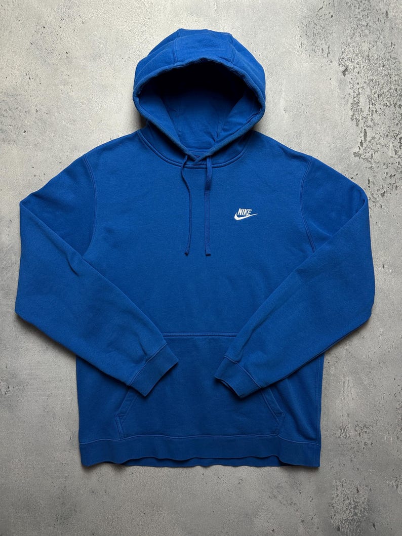 Peut inclure: Un sweat-shirt &agrave; capuche bleu avec un logo Nike blanc sur le devant.
