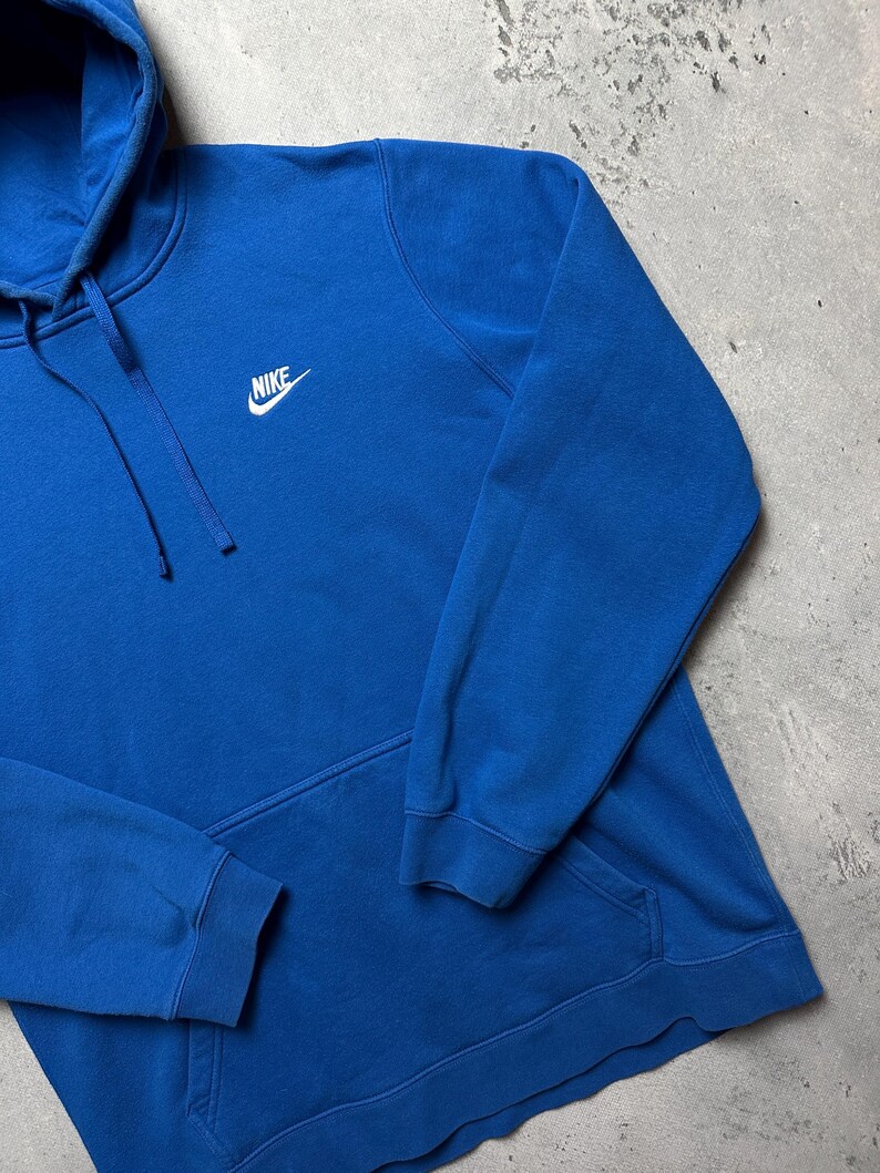 Peut inclure: Un sweat-shirt &agrave; capuche bleu avec un logo Nike blanc sur le devant.