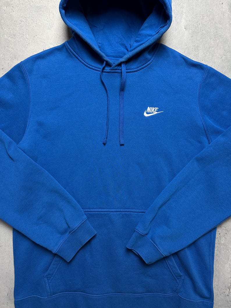 Peut inclure: Un sweat-shirt &agrave; capuche bleu avec un logo Nike blanc sur le devant.