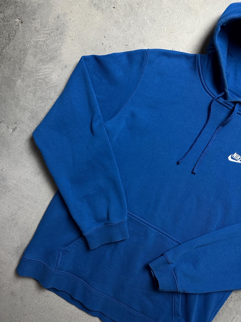 Peut inclure: Un sweat &agrave; capuche bleu royal avec un logo Nike blanc en forme de virgule sur la poitrine gauche.