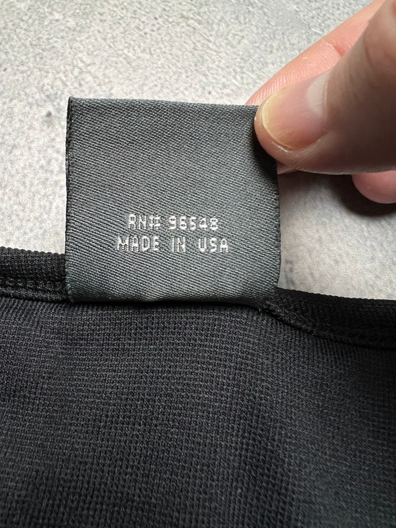 May include: Black fabric tag with white text that reads "RN# 96548 MADE IN USA".