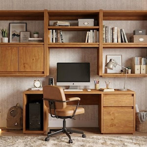 May include: A wooden desk and wall-mounted shelving unit featuring a computer monitor, a tan office chair, and storage compartments. The desk includes a drawer and cabinet, while the shelves hold books, decorative boxes, and a desk lamp.