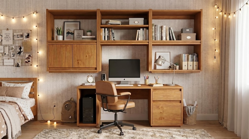 May include: A wooden desk and wall-mounted shelving unit featuring a computer monitor, a tan office chair, and storage compartments. The desk includes a drawer and cabinet, while the shelves hold books, decorative boxes, and a desk lamp.