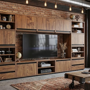 May include: A large wall-mounted wooden entertainment unit featuring a central television compartment, multiple open shelving units, and lower storage cabinets with dark horizontal accents, constructed from a rich brown wood grain finish.