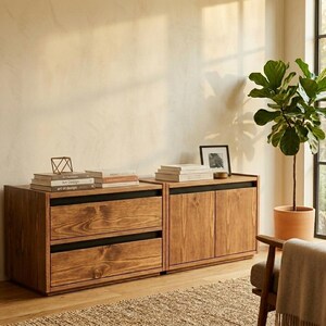 May include: A low-profile wooden storage unit featuring two stacked drawers on the left and a two-door cabinet on the right. The piece is constructed from light brown wood with visible grain and accented by horizontal black recessed drawer pulls.