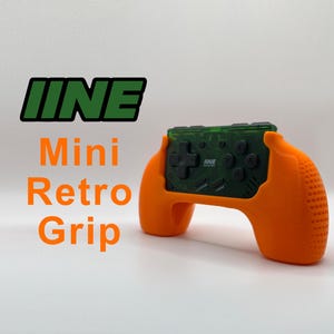 May include: Orange and green handheld video game controller with a retro design. The controller has a textured grip and the text "IIINE Mini Retro Grip" is visible in the image.