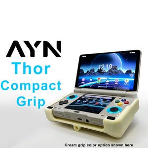 May include: A handheld gaming device with a cream-colored grip. The screen displays a digital landscape with a time of 12:19. The device has multiple buttons in various colors. The text "AYN Thor Compact Grip" is visible.