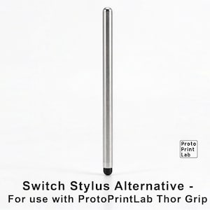May include: A silver-colored cylindrical stylus with a rounded top and a black tip at the base. The text "Proto Print Lab" appears in a small square box, and the text "Switch Stylus Alternative - For use with ProtoPrintLab Thor Grip" is below.