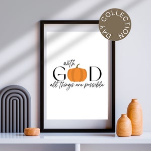 May include: A framed print with a white background and black text that reads "with GOD all things are possible". A small orange pumpkin is centered in the text. The print is framed in black and is sitting on a white shelf with two wooden vases and a gray arch.