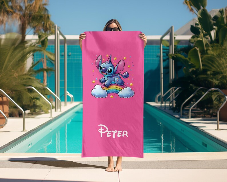 May include: Pink beach towel with a blue Stitch character riding a rainbow. The towel has the name "Peter" printed on it.