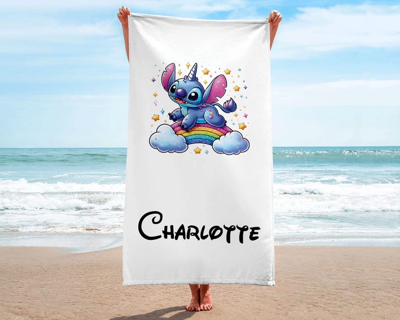 May include: A white beach towel with a blue Stitch character riding a rainbow. The towel has the name "Charlotte" printed on it.