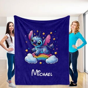 May include: A blue fleece blanket with a cartoon Stitch character riding a rainbow. The blanket has a starry background and the name "Michael" is printed on the bottom.