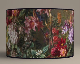 Può includere: Un paralume cilindrico con una stampa floreale che presenta una varietà di fiori in tonalità di rosa, rosso, viola e bianco. I fiori sono disposti in uno stile botanico lussureggiante su uno sfondo verde scuro.