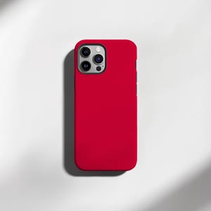 May include: A vibrant red phone case with a glossy finish. The case has a rectangular shape with rounded corners and a camera cutout. The phone case is designed to fit a smartphone and protect it from damage.