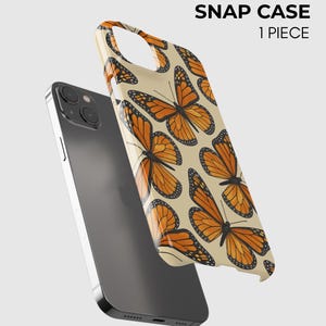 Może przedstawiać: Ciemnoszary smartfon w połączeniu z etui typu snap w kolorze kremowym, ozdobionym powtarzającym się wzorem pomarańczowo-czarnych motyli monarch&oacute;w. Tekst SNAP CASE 1 PIECE jest nadrukowany na czarno w prawym g&oacute;rnym rogu obrazu.