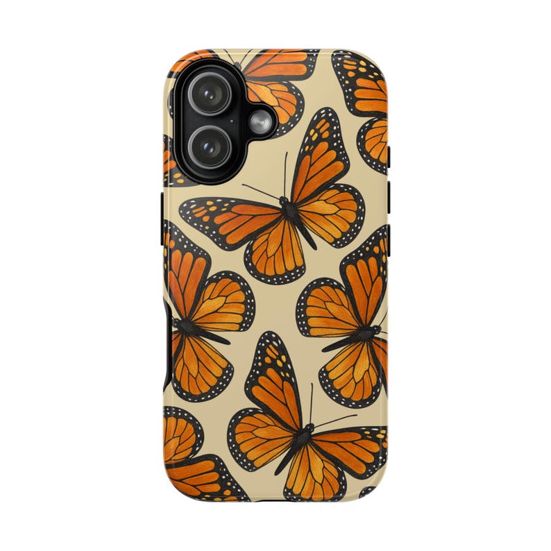 Może przedstawiać: Etui na telefon z powtarzającym się wzorem pomarańczowo-czarnych motyli monarch&oacute;w na jasnobeżowym tle. Etui posiada czarne wycięcie na aparat w lewym g&oacute;rnym rogu, zaprojektowane dla systemu z dwoma obiektywami i lampą błyskową.
