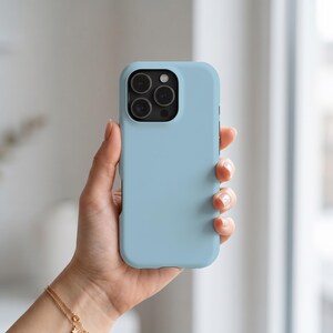 May include: A solid light blue smartphone case with a smooth matte finish. The case features a rectangular cutout in the upper left corner for a triple-lens camera system, with the black lenses clearly visible within the protective housing.