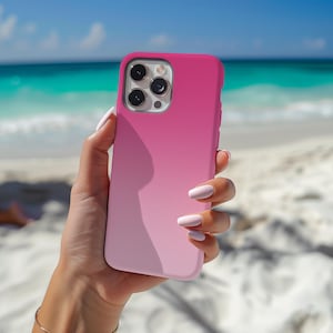 May include: A smartphone case featuring a smooth, matte finish with a vertical gradient color scheme that transitions from a vibrant hot pink at the top to a soft, pale pastel pink at the bottom, including a cutout for a triple-lens camera system.