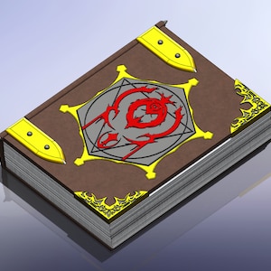 Pode incluir: Um livro encadernado em couro marrom com detalhes dourados e um símbolo vermelho e preto na capa. O livro está fechado e tem uma lombada grossa.