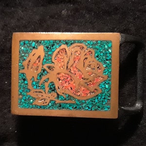 May include: A brass belt buckle with a rose design inlaid with turquoise and coral stones.
