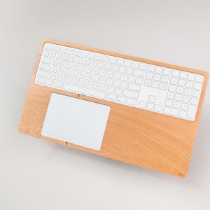 May include: A wooden keyboard and trackpad combo with a white keyboard and a white trackpad. The wood has a light brown color. The keyboard is a standard size with white keys.