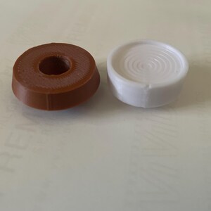 May include: Two round, flat, decorative pieces. One is brown with a hole in the centre and the other is white with a spiral design.