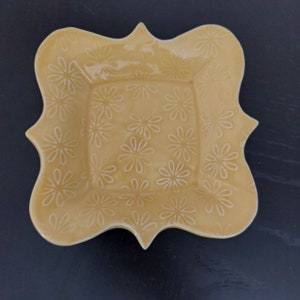 May include: A yellow ceramic serving dish with a scalloped edge and a floral pattern.