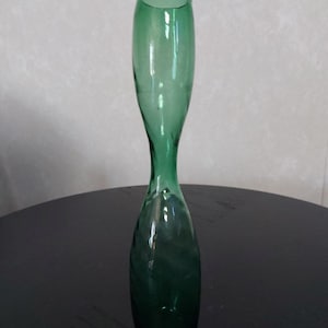 May include: A tall, slender green glass vase with a rounded bottom and a narrow opening.
