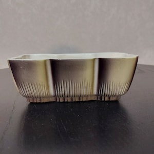 以下が含まれることがあります： 茶色と黄色の釉薬をかけた長方形のセラミックプランター。プランターは波打った縁とリブのデザインをしています。