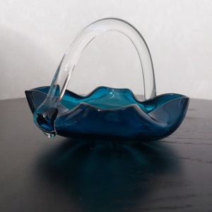 May include: A teal blue glass bowl with a clear glass handle. The bowl has a wavy edge and is perfect for serving snacks or fruit.