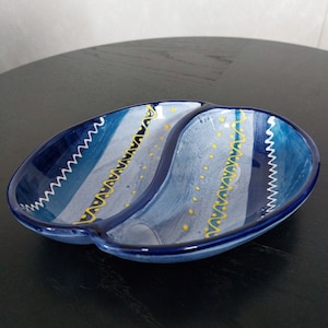 May include: A blue and white ceramic serving dish with a yellow and white design. The dish is divided into two sections.