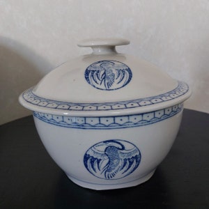 Puede incluir: Un tazón de cerámica blanca con un diseño azul y blanco de un pájaro. El tazón tiene una tapa con un diseño a juego.