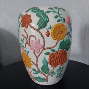 Puede incluir: Jarrón de cerámica blanco con superficie texturizada y diseño floral en relieve. Las flores son en tonos de rosa, naranja, amarillo y verde.