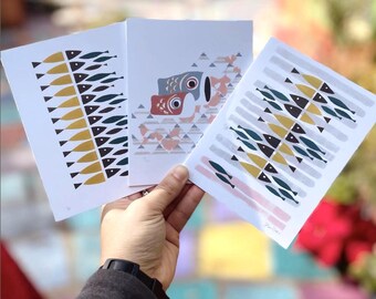 May include: Three art prints featuring fish designs. One print displays rows of yellow and dark blue fish. Another showcases two fish with red and gray details. The third print has a pattern of yellow, dark blue, and black fish.