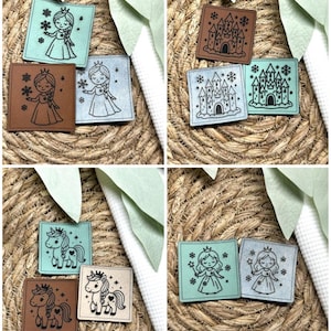 Könnte beinhalten: Eine Sammlung quadratischer Lederaufnäher mit Märchenmotiven. Die Aufnäher zeigen Illustrationen von Prinzessinnen, Burgen und Einhörnern in verschiedenen Farben, darunter Braun, Blau und Mintgrün. Die Aufnäher sind auf einer gewebten Oberfläche angeordnet.