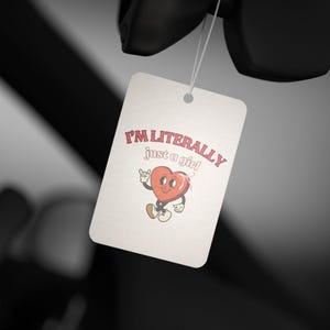 Puede incluir: Una etiqueta rectangular blanca con el texto "I'M LITERALLY just a girl" en rosa y un personaje de corazón de dibujos animados. El corazón tiene brazos, piernas y una cara, y hace un gesto de rock.