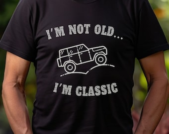 Puede incluir: Un hombre con una camiseta negra con un gráfico blanco de un jeep y el texto "I'm not old... I'm classic".