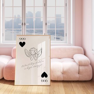 May include: A black and white illustration of an angel with wings, with the text "It's time to let go of what is no longer serving you" and the numbers 999 and 666. The illustration is framed and hanging on a wall.
