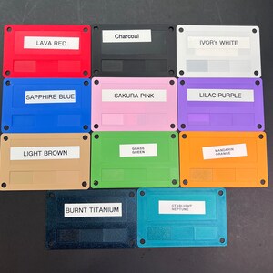 May include: Ten color swatches on rectangular plastic cards with rounded corners. The colors are: Lava Red, Charcoal, Ivory White, Sapphire Blue, Sakura Pink, Lilac Purple, Light Brown, Grass Green, Mandarin Orange, Burnt Titanium, and Starlight Neptune.