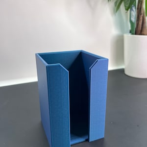 May include: A blue cardboard organizer with a single open compartment. The organizer is sitting on a black surface.