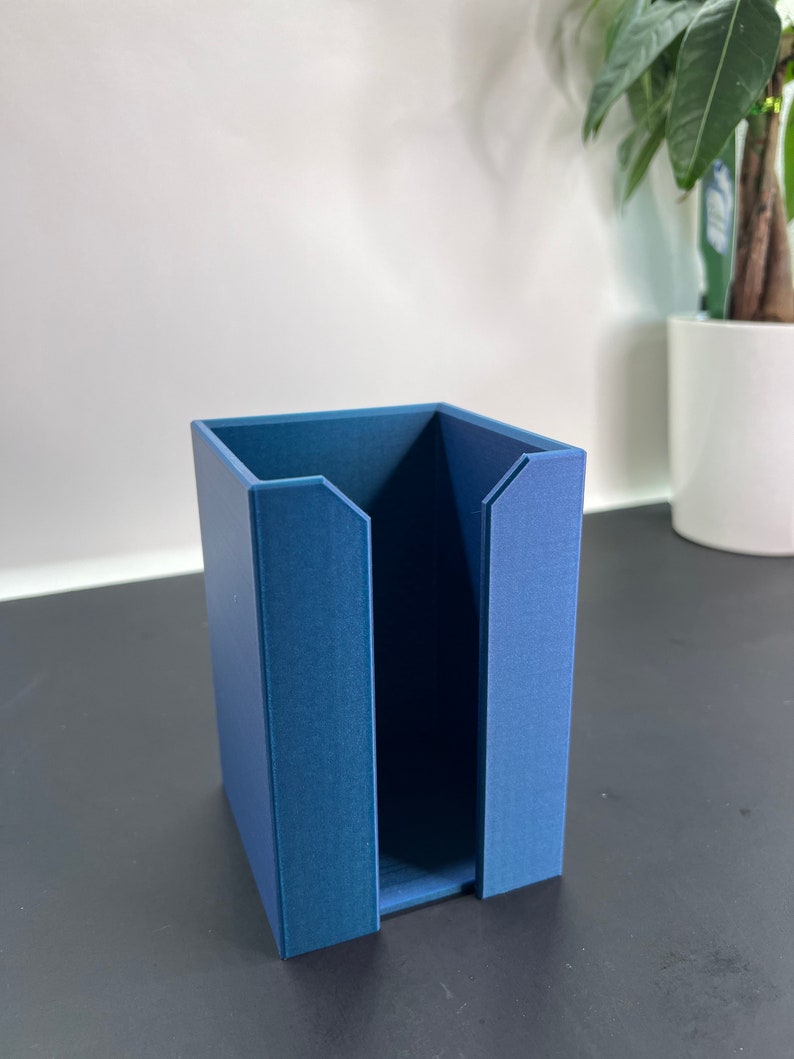 May include: A blue cardboard organizer with a single open compartment. The organizer is sitting on a black surface.